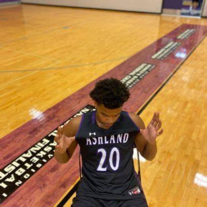 Maceo Williams is sitting in a chair showing his jersey.